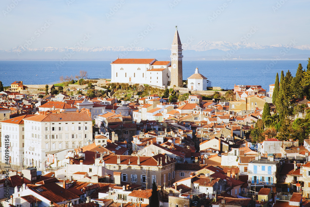 Fototapeta premium Red roofs of the historical center of old town Piran with main church against the sunset sky and Adriatic sea. Aerial view, Slovenia