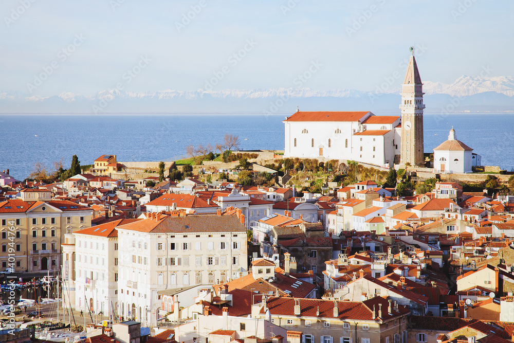 Fototapeta premium Red roofs of the historical center of old town Piran with main church against the sunset sky and Adriatic sea. Aerial view, Slovenia
