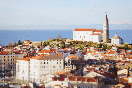 Red roofs of the historical center of old town Piran with main church against the sunset sky and Adriatic sea. Aerial view, Slovenia