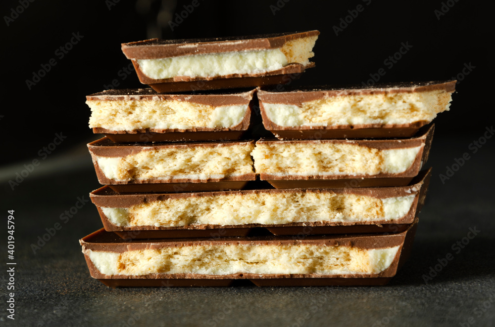 Stack of delicious crunchy milky chocolate with cookies on the dark surface