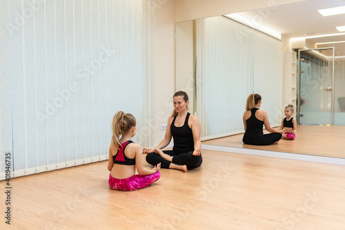 mother yoga instructor and daughter are meditating in the Lotus position