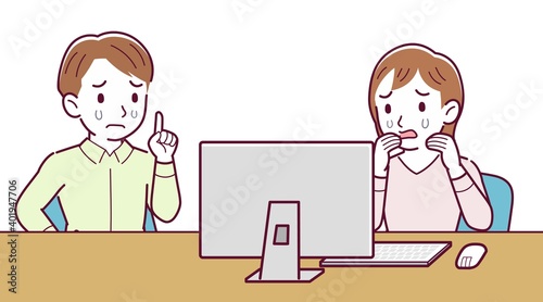 Two people talking while looking at a desktop computer