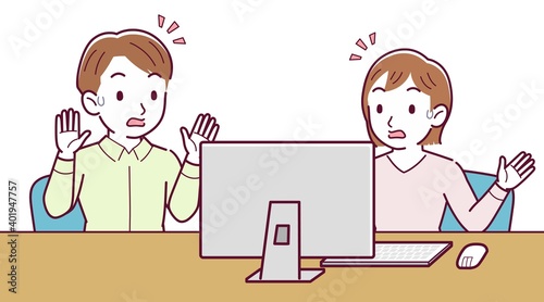 Two people talking while looking at a desktop computer