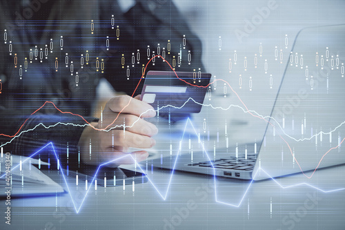 Multi exposure of woman on-line shopping holding a credit card and financial graph drawing. Stock market E-commerce concept.