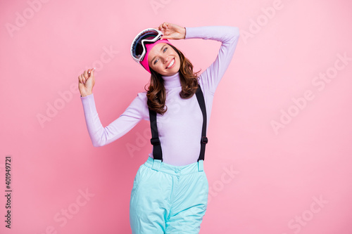 Photo of charming sweet curly young lady skier dressed jumper headwear goggles dancing isolated pink color background