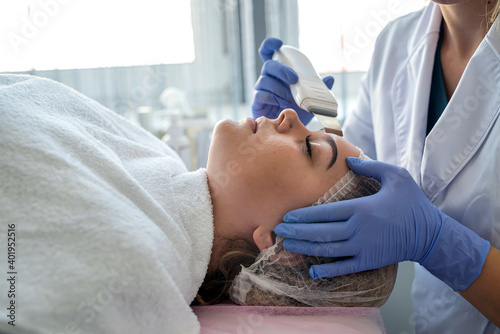 Doctor doing procedure of ultrasonic cleaning of face patient in beauty salon