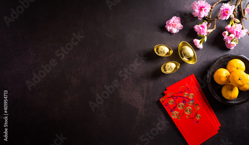 Chinese new year festival decorations pow or red packet, and gold ingots or golden lump on dark stone background. Chinese characters FU in the article refer to fortune good luck, wealth, money flow.