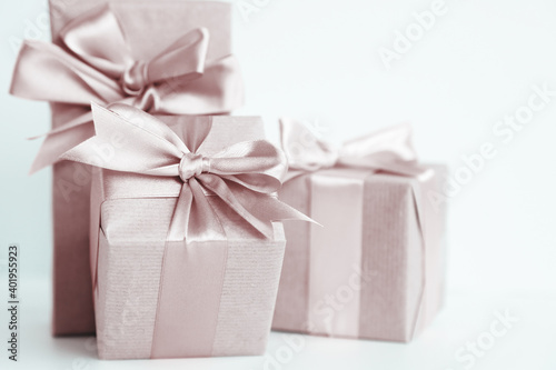 Three brown paper gift boxes with beautiful satin ribbon, monochrome toned design, pastel colors. Universal gifts design for all kind of shopping and celebration