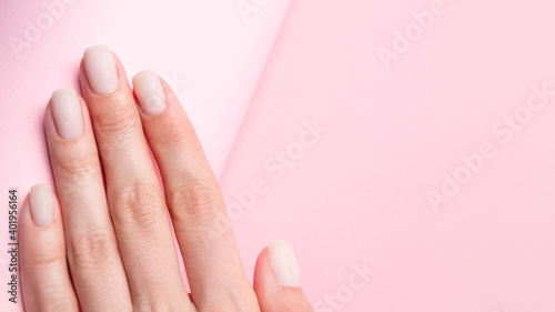 Matt nude nails close up on the trendy pink background with copy space