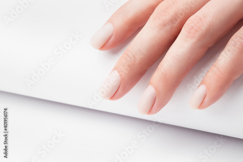 Matt nude nails close up on the trendy light background, woman manicure