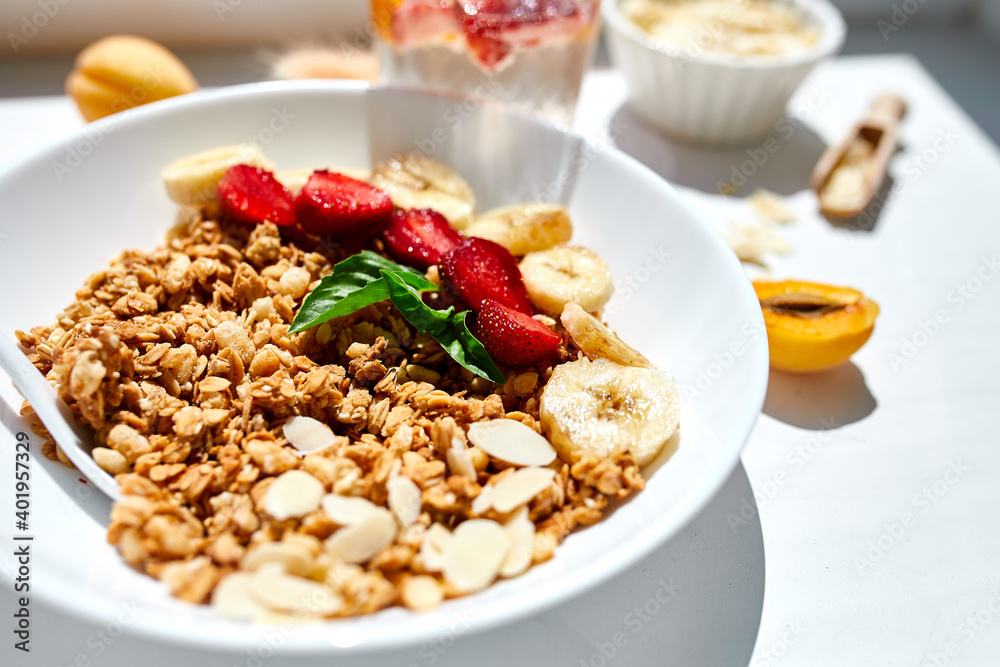 Healthy breakfast bowl, fresh granola, muesli berries strawberry, banana on white table in hard lights, Top view, Copy space. Clean eating, detox, dieting, vegetarian food concept Healthy breakfast bowl, fresh granola, muesli berries strawberry, banana on white table in hard lights, Top view, Copy space. Clean eating, detox, dieting, vegetarian food concept