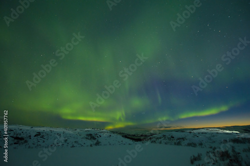 Northern lights in the sky. Snowy tundra at night. © Moroshka
