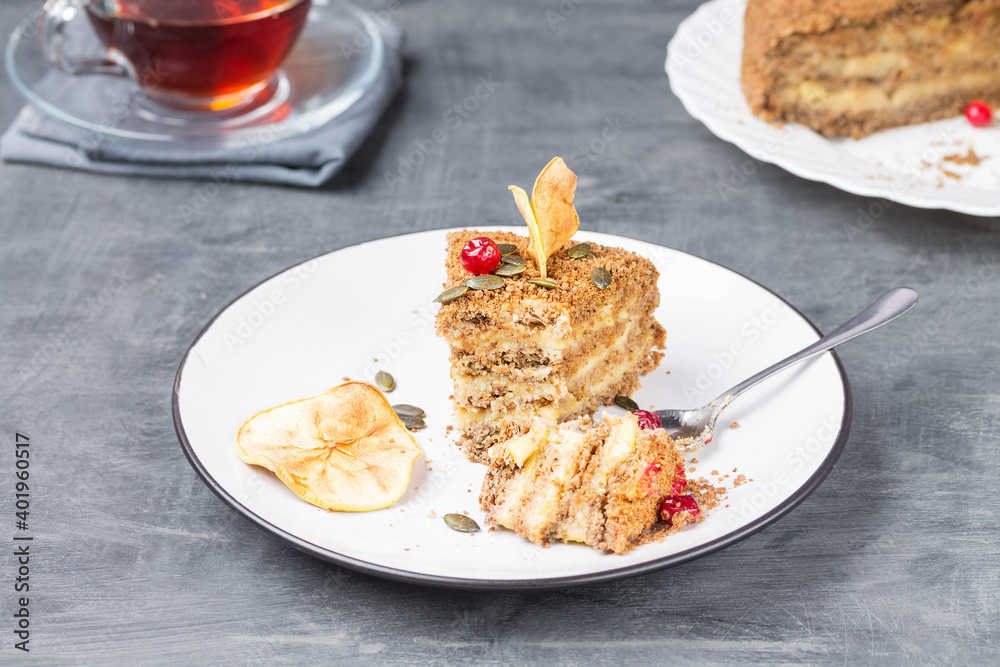 A broken piece of gluten-free nut cake with creamy Apple filling on a plate with a Cup of tea and a large cake in the background. A broken piece of gluten-free nut cake with creamy Apple filling on a plate with a Cup of tea and a large cake in the background.