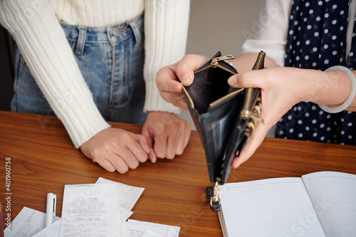 Senior mother showing empty purse to adult daughter and complaining about lack of money for paying utility bills