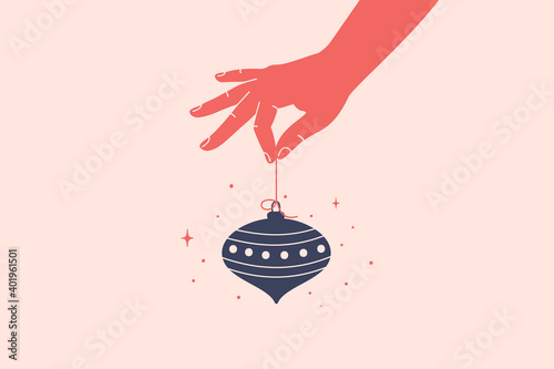 Merry Christmas and Happy New Year concept with human hand holds hanging Xmas toy. Vector illustration in flat style.