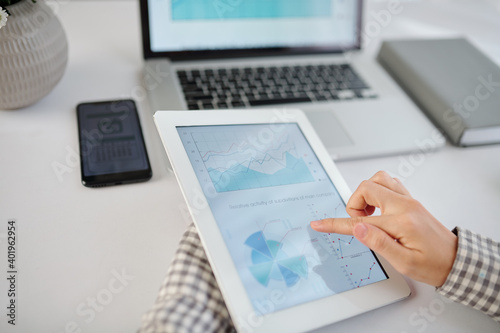Close-up image of businesswoman checking diagram on screen of digital tablet when working at office desk