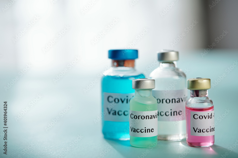 Four vials with different vaccines against coronavirus on table in medical office
