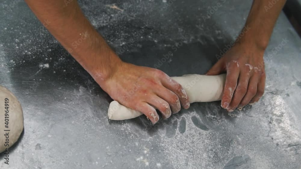 The man is kneading the dough. Hamburger buns. Bakery, production. bread, baguette, flour and water. The man is kneading the dough. Hamburger buns. Bakery, production. bread, baguette, flour and water.