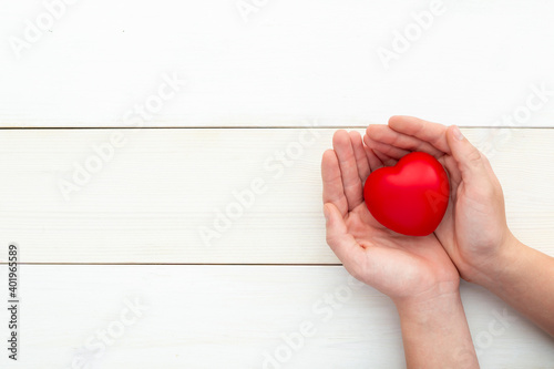Fototapeta Naklejka Na Ścianę i Meble -  hands holding red heart, health care, love, valentine, helpless, donation, mindfulness, wellbeing, family insurance and CSR, world heart day, world health day. Flatly, top view, copy space.