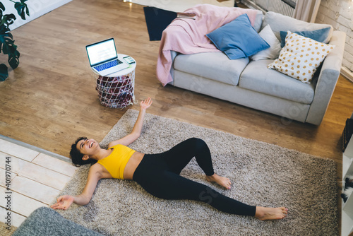 Wallpaper Mural Joyful fit girl in tracksuit lying on rug and laughing during break from home workout and aerobic practice in morning, mock up laptop computer with copy space area for sportive advertising text Torontodigital.ca