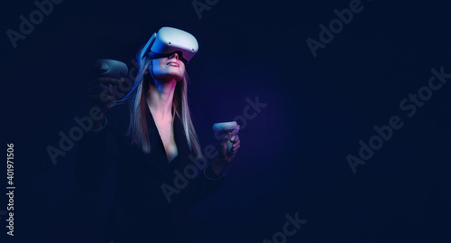 young woman with blond hair in a vr helmet looks around with surprise and delight photo