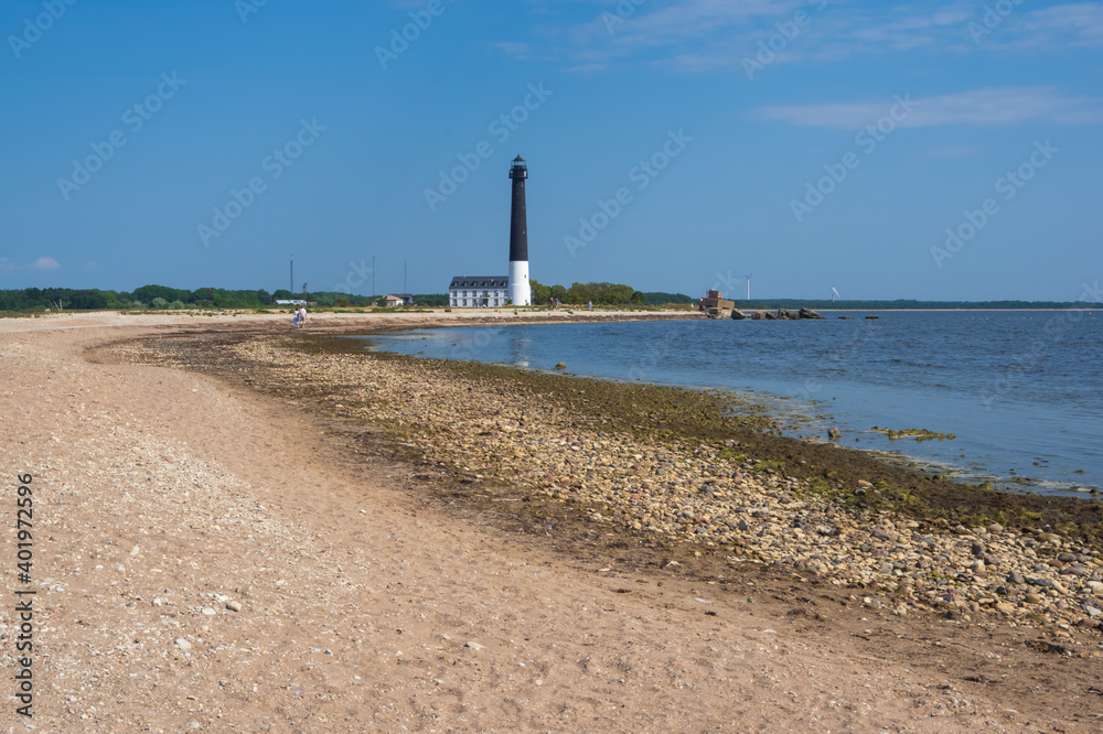 
View to the beach of Sõrve peninsula cape with sand and pebbles by coastline. Lighthouse in the background. 
