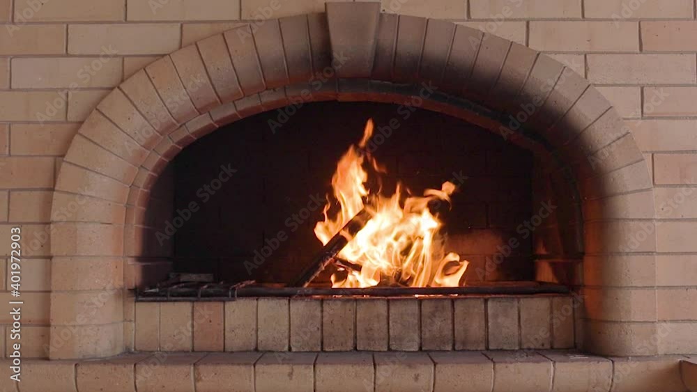 A brick fireplace with a fire burning in it.Flames walk on the surface of the wood. A brick fireplace with a fire burning in it.Flames walk on the surface of the wood.