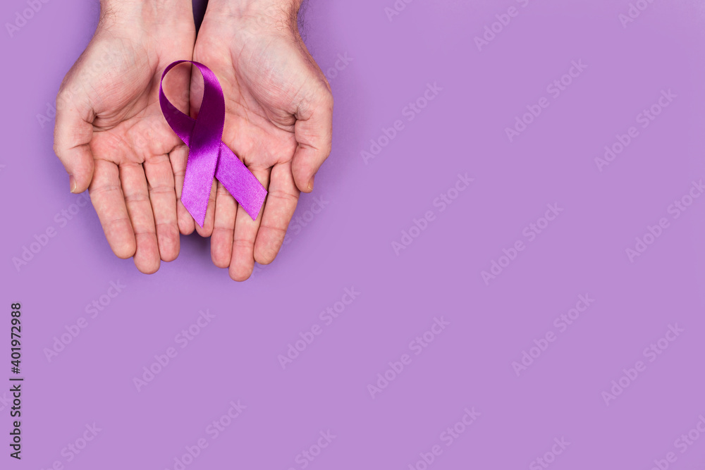 Manos de mujer sosteniendo una cinta lazo morado sobre fondo de color morado liso y aislado. Vista superior. Copy space. Concepto: Cancer Manos de mujer sosteniendo una cinta lazo morado sobre fondo de color morado liso y aislado. Vista superior. Copy space. Concepto: Cancer