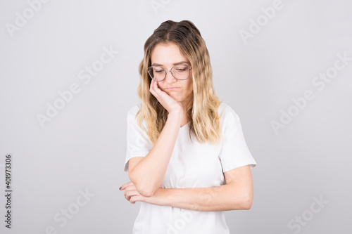 A girl in a white T-shirt looks down tired. The concept of fatigue, stress and overwork.