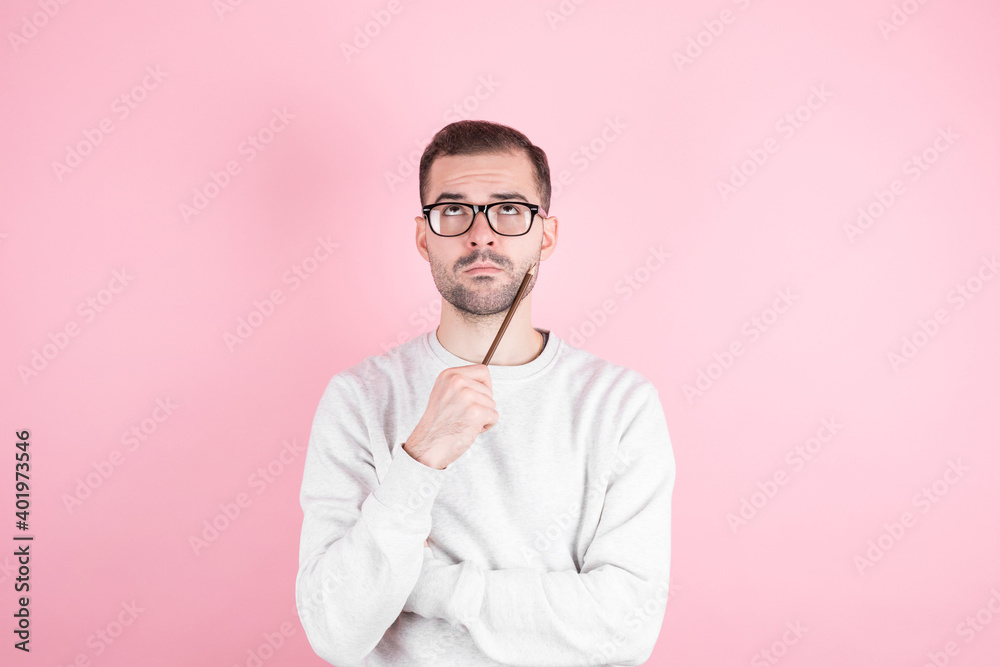 Portrait of young man thinking with pencil to her head and looks to the side Portrait of young man thinking with pencil to her head and looks to the side