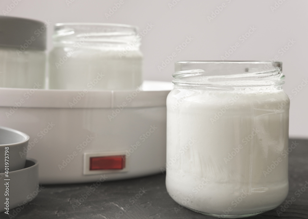 homemade organic yogurt in glass jars near yogurt maker. automatic yogurt machine to make fermented milk product at home. yogurt or kefir making during quarantine concept. homemade organic yogurt in glass jars near yogurt maker. automatic yogurt machine to make fermented milk product at home. yogurt or kefir making during quarantine concept.