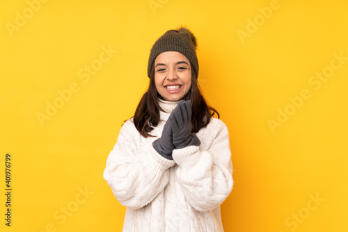 Young woman with winter hat over isolated yellow background applauding after presentation in a conference © luismolinero