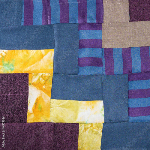 textile background - stitched detail of patchwork cloth from blue and yellow fabrics