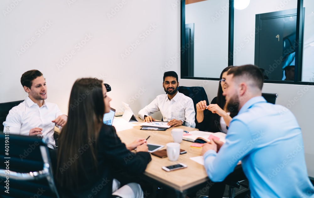 Businessman talking with blurred colleagues at table in office Businessman talking with blurred colleagues at table in office