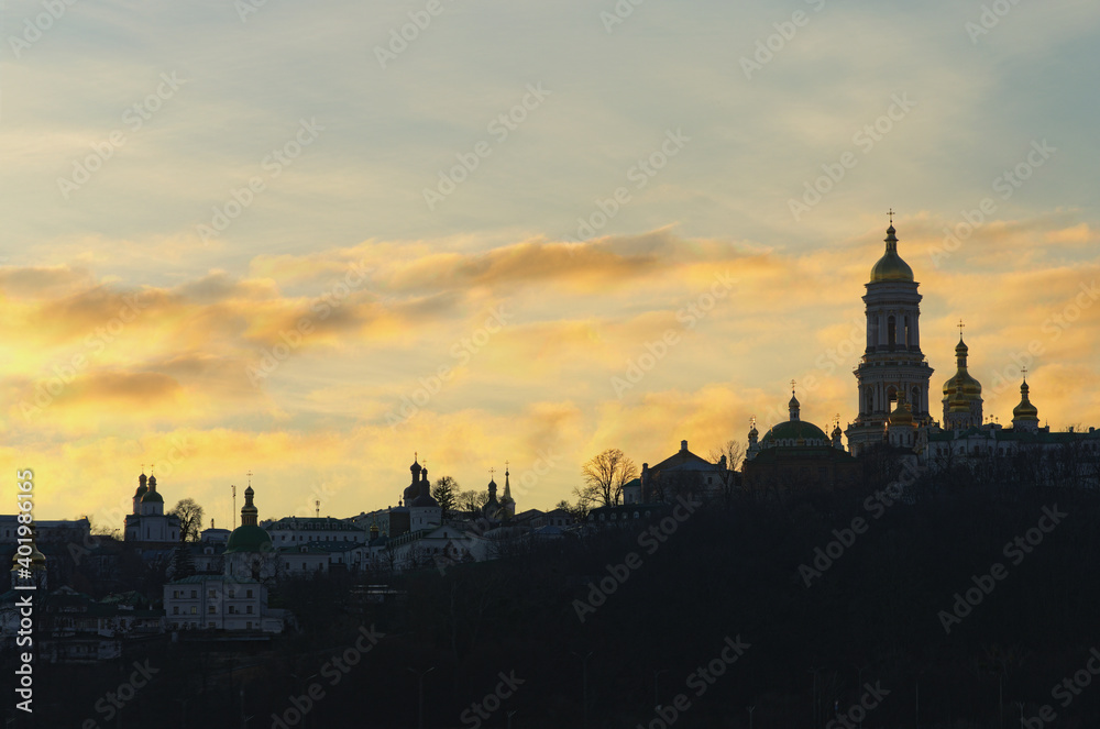 Astonishing winter view of famous Kyiv's hills against cloudy sky during sunset. Landscape of ancient Kyiv Pechersk Lavra. It is a historic Orthodox Christian monastery.Christian Orthodox cathedral