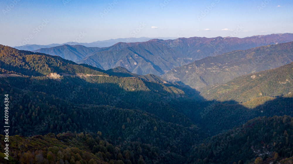 A panoramic shot of a scenery that captures mountains under the sky. Different shades of the scenery creates this photo's aesthetic.