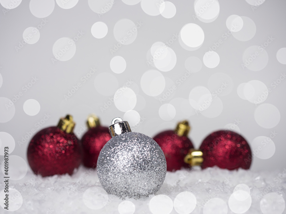One silver ball on the Christmas tree and four red balls in the back, on a bokeh background, on top there is a place for an inscription. One silver ball on the Christmas tree and four red balls in the back, on a bokeh background, on top there is a place for an inscription.