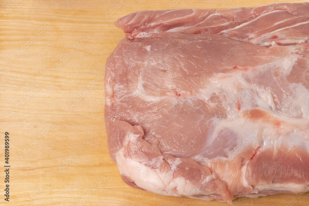 The raw pork fillet on the brown chopping board close-up The raw pork fillet on the brown chopping board close-up
