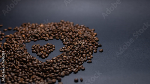 heap of coffee beans on black background. Coffee beans pile isolated on black background. Culinary coffee background. heart shaped coffee beans top view