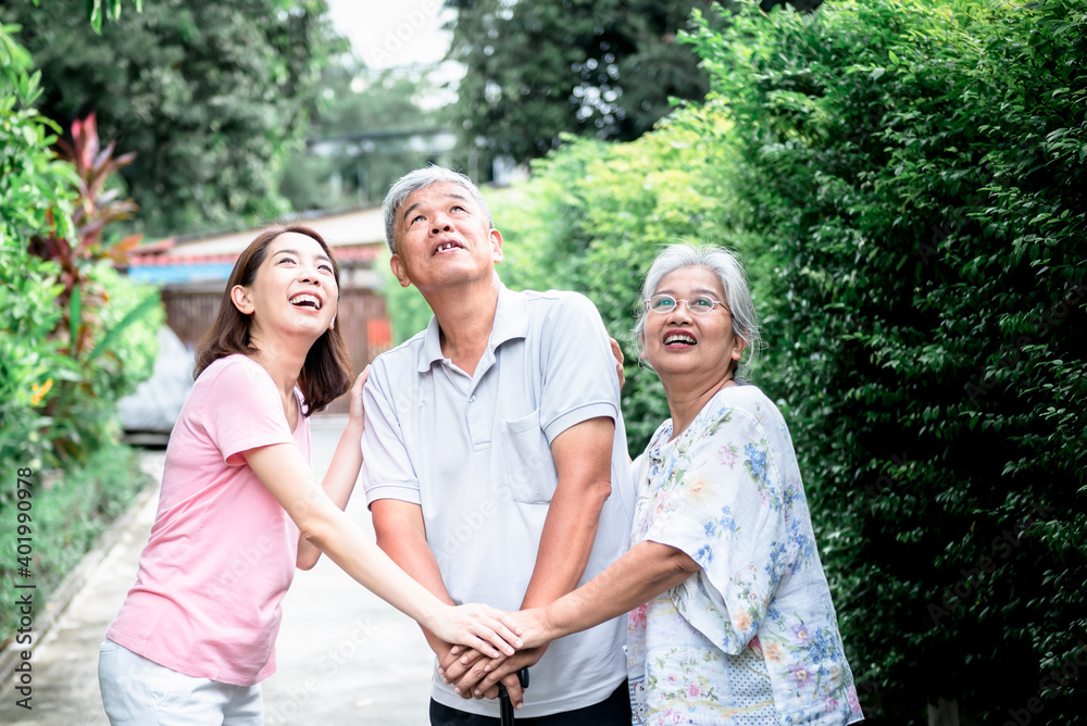 Asian family, an elderly couple and a daughter, They are looking up and all holding hands to encourage each other, concept to relationship and health care in family.