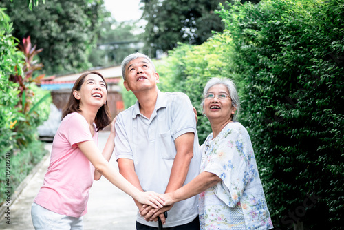 Asian family, an elderly couple and a daughter, They are looking up and all holding hands to encourage each other, concept to relationship and health care in family.