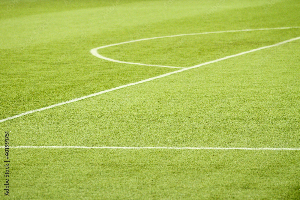 Large area of a football field, with its white lines, the half moon and the green of the synthetic grass.