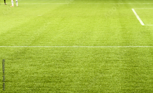 Large area of a football field  with its brancase lines highlighting the green of the synthetic grass