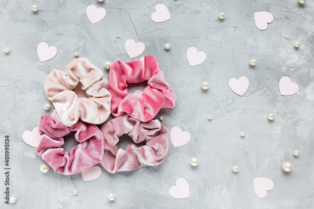 Obraz premium Four trendy velvet scrunchies, pastel pink paper hearts and white pearls on gray background. Diy accessories and hairstyles for Valentines Day, fashion and lifestyle concept, copy space