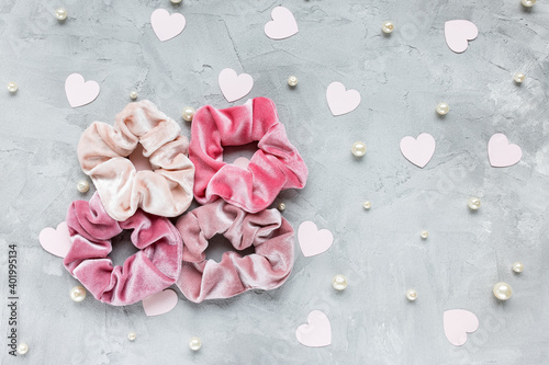 Fototapeta Naklejka Na Ścianę i Meble -  Four trendy velvet scrunchies, pastel pink paper hearts and white pearls on gray background. Diy accessories and hairstyles for Valentines Day, fashion and lifestyle concept, copy space