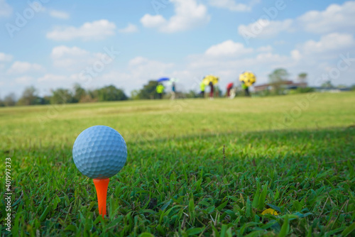 Golf ball on tee in the evening golf course with sunshine background.