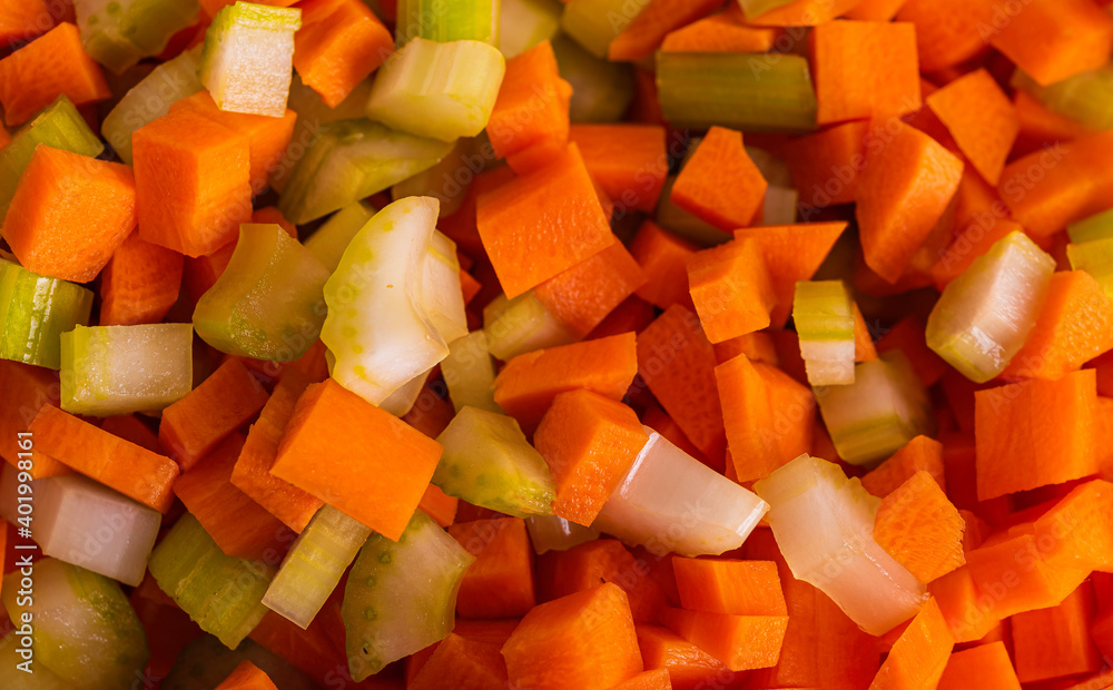 Carrots, Onions and Celery being Sliced on White Cutting Board With Chef's Knife and Wood Stand in a Bowl Carrots, Onions and Celery being Sliced on White Cutting Board With Chef's Knife and Wood Stand in a Bowl