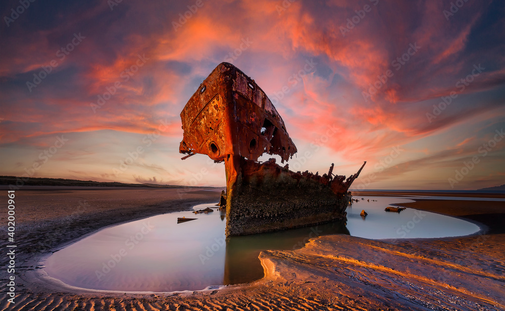 Fototapeta premium Shipwrecked off the coast of Ireland, An shipwreck or abandoned shipwreck,,boat Wreck Sunset light at the beach, Wrecked boat abandoned stand on beach or Shipwreck
