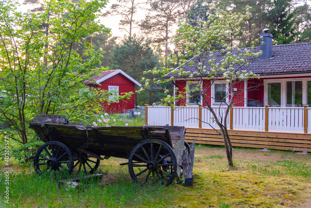 old wooden trailer cart at a countryside yard under the trees near swedish house scandinavian style