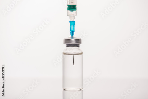 SarsCov-2 vaccination concept. Cropped close up view photo of vial with transparent liquid and syringe with needle isolated white background
